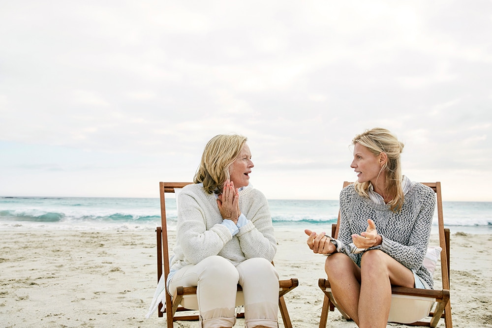 Two women sitting on a beach talking