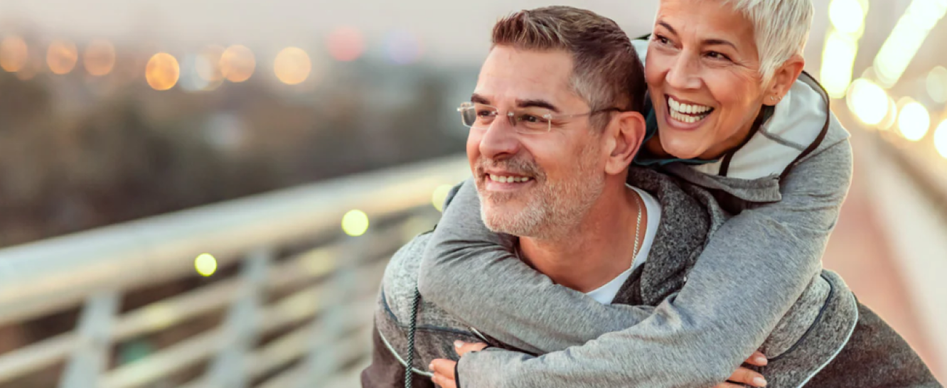 A man giving a woman a piggy back and they are both laughing