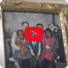 image of family photo with two adults and three children with a red play button in the center