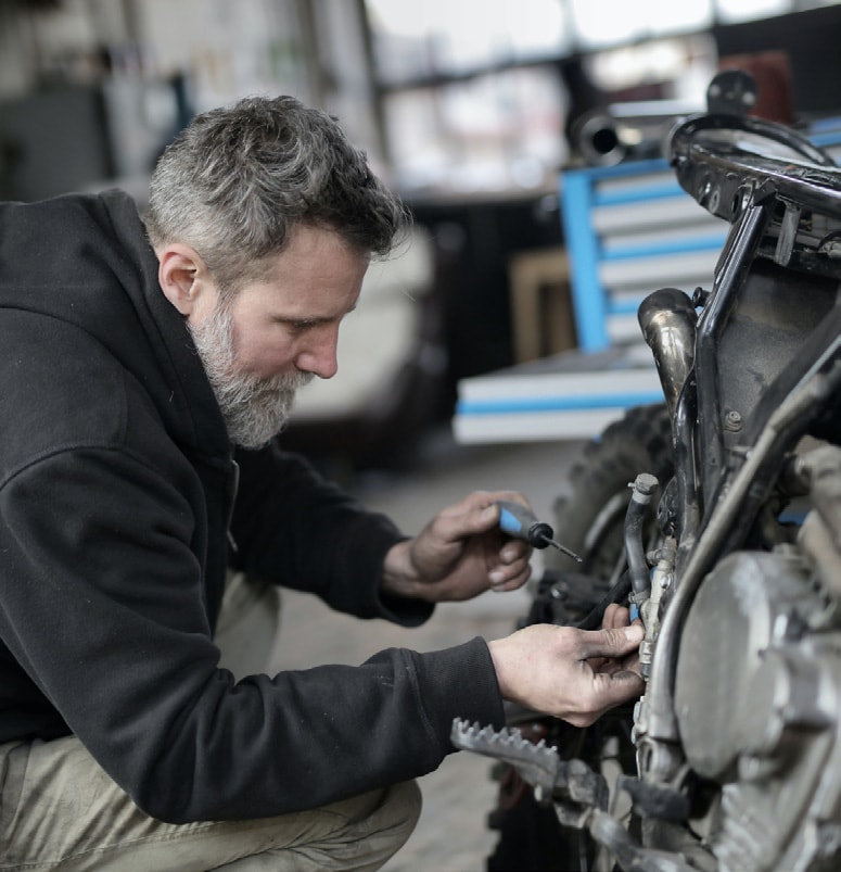 Male in black hoodie fixing a motorcycle