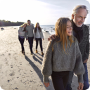 Family walking along the beach. Father and daughter in the foreground and other family in the background.