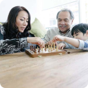 Mother and son playing chess while grandfather looks on