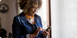 A woman scrolling through her phone smiling