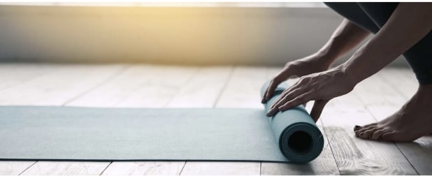 Image of hands rolling up a yoga mat