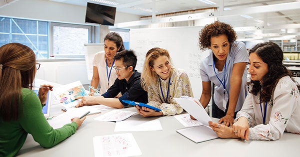 Group of mostly female co-workers sitting around an office table looking at paperwork