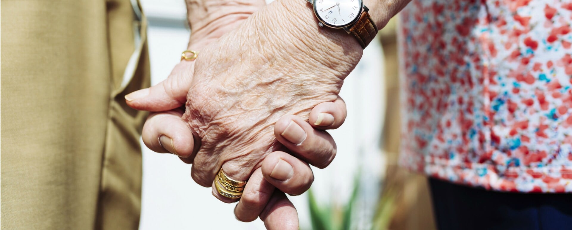 Two hands of elderly people holding one another