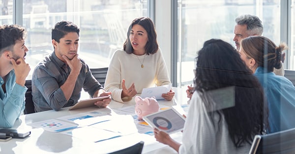 business professionals sitting around a conference table collaborating in a conference room surrounded by windows