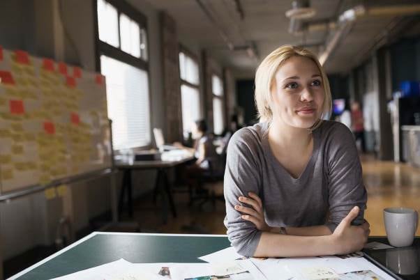 woman in grey long sleeve top and blonde hair smiling while sitting at table