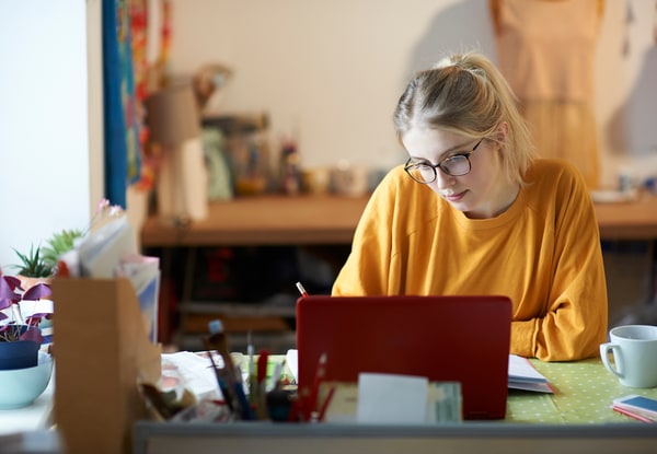 female in orange sweater and glasses working at a table