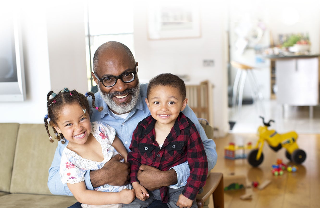 Grandfather holding his grandchildren in his home